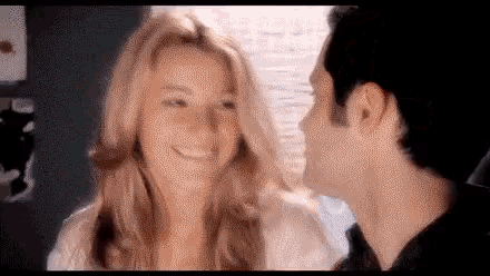 a man is kissing a woman on the cheek while she smiles .