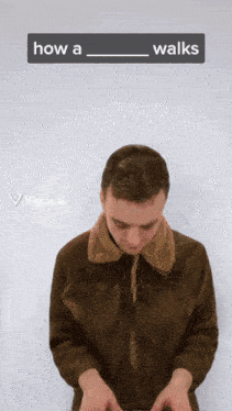 a man in a brown jacket is standing in front of a white wall with a sign that says how a walks