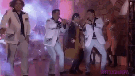 a group of men in white suits are dancing on a stage .
