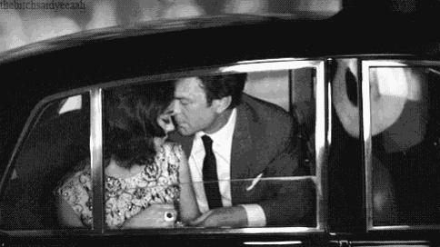 a man and a woman are kissing in the back of a car .
