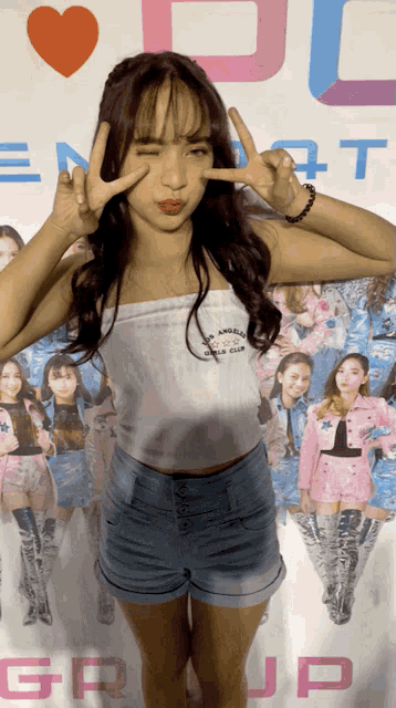 a girl giving a peace sign in front of a poster that says group