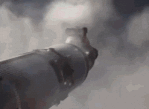 a close up of a person 's hand holding a gun with smoke coming out of it