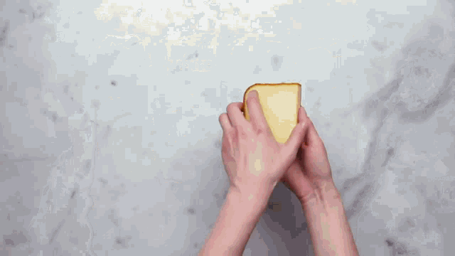 a person is spreading vanilla frosting on a piece of cake .