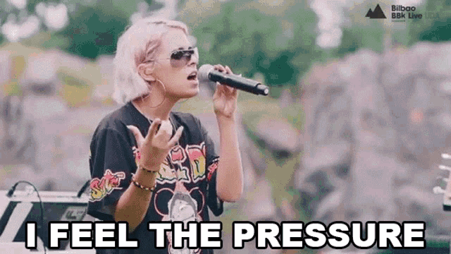 a woman singing into a microphone with the words " i feel the pressure " written below her