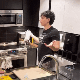 a man standing in a kitchen wearing a black shirt that says ' i love you ' on it