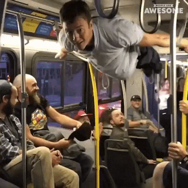 a man is hanging upside down on a bus with the word awesome written above him