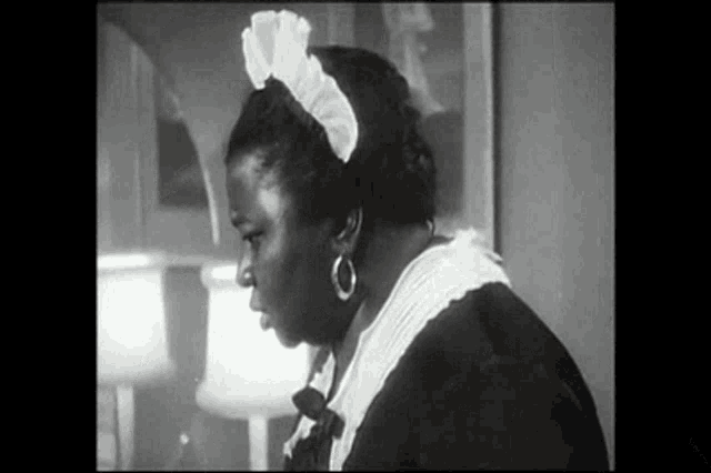 a black and white photo of a woman wearing a maid outfit