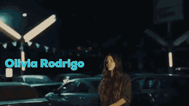 olivia rodrigo is standing in a parking lot