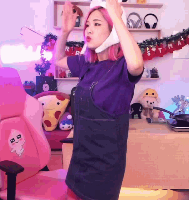 a woman in a purple shirt is standing in front of a christmas banner