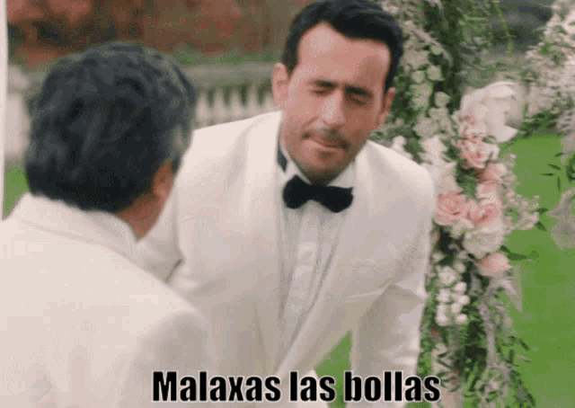 a man in a white suit and bow tie says malaxas las bollas in spanish