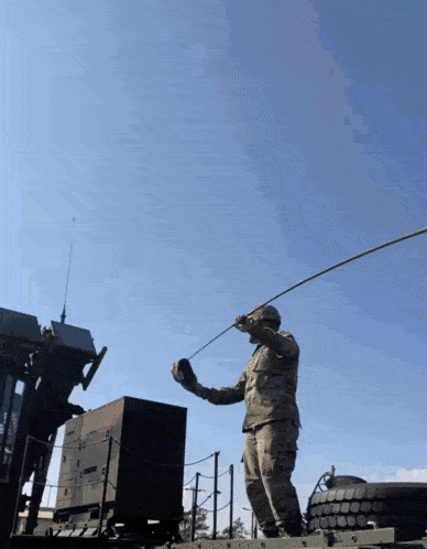 a soldier is standing on top of a military vehicle