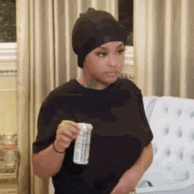 a woman wearing a black hat is holding a can of soda in her hand .