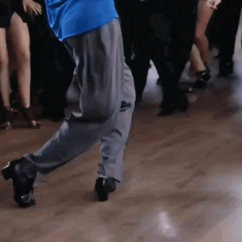 a man in a blue shirt and grey pants is dancing