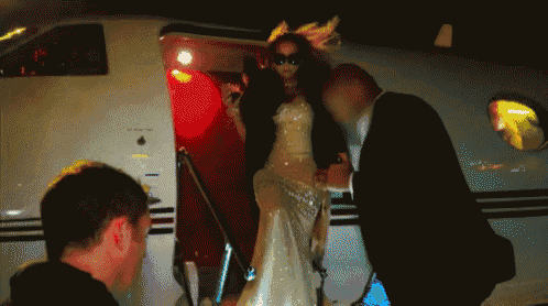 a woman in a white dress is walking out of a private jet