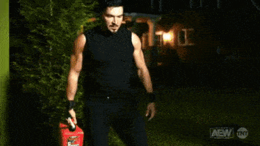 a man in a black tank top and black pants is holding a red gas can .