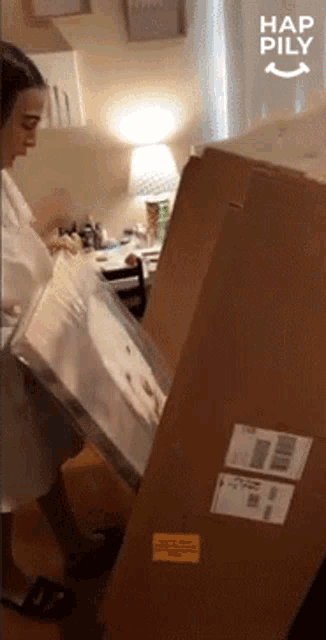 a woman standing next to a cardboard box that says hap pily