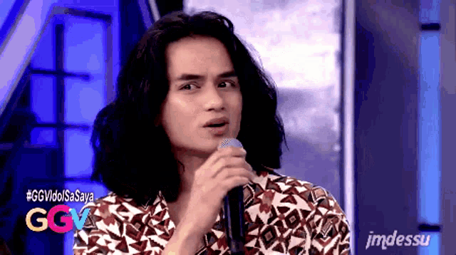 a man with long hair is singing into a microphone with ggv idol saya written on the bottom