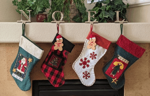 four christmas stockings are hanging on a mantle with the word noel behind them