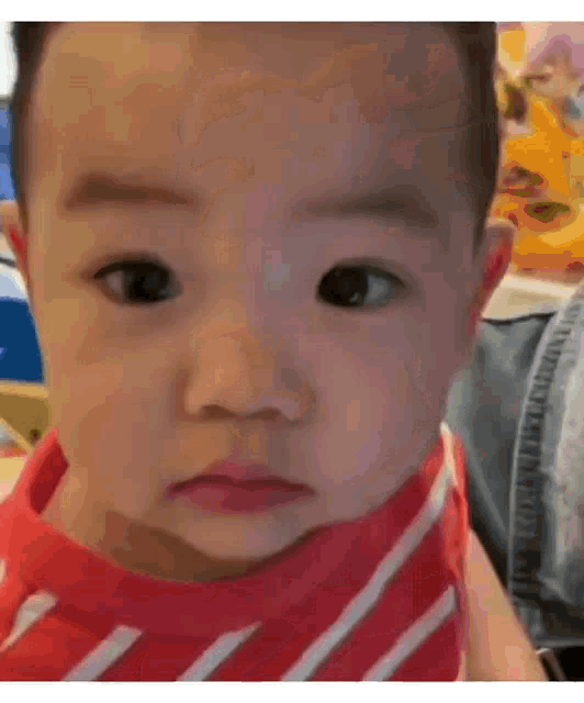 a baby in a red and white striped shirt is being held by a person .