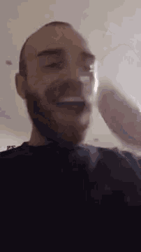 a man with a beard is holding a glass in his hand and smiling .