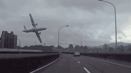 a plane is flying over a highway with cars driving down it .
