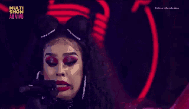 a woman is singing into a microphone while wearing a cat ear headband .