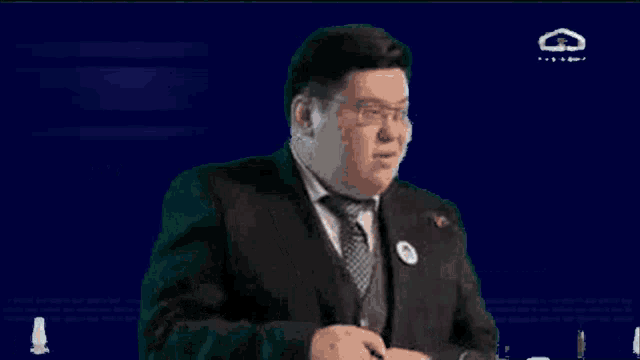 a man in a suit and tie is sitting in front of a screen that says brain on it