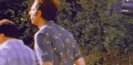 a blurry picture of two men standing next to each other in front of trees .