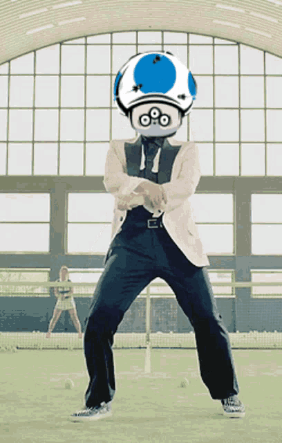 a man in a suit with a blue and white mushroom on his head is dancing on a tennis court