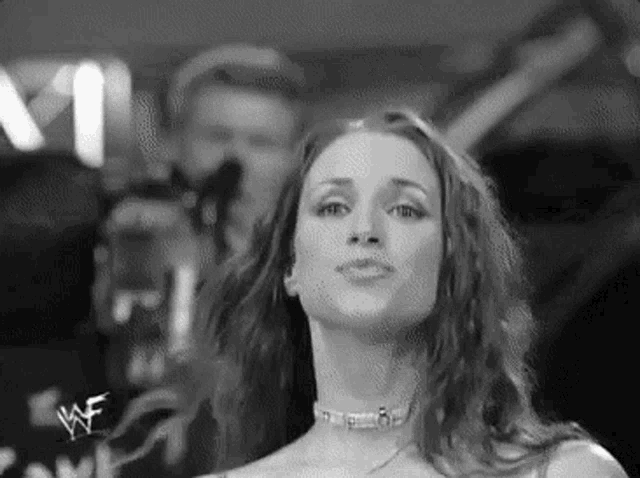 a black and white photo of a woman with long hair and a choker .