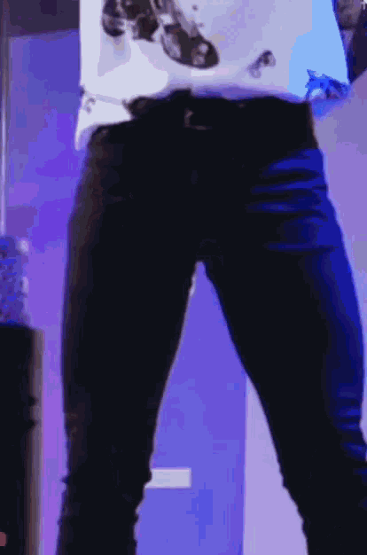 a person wearing a white shirt and black jeans is standing in front of a blue wall .