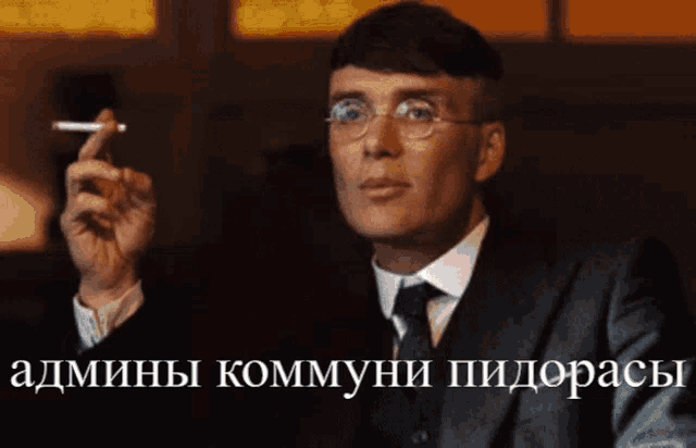a man in a suit and tie is smoking a cigarette with a caption in russian that says admini kommyni pidoracy