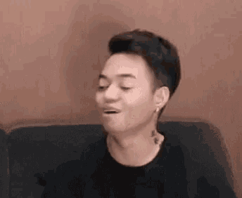 a young man is sitting on a couch with his mouth open and making a funny face .