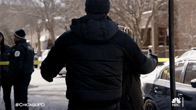 a man in a black jacket is hugging another man in a chicagopd scene