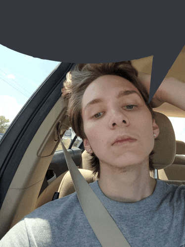 a young man sitting in a car with his head in his hand