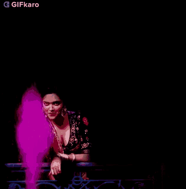 a woman is sitting on a balcony with a purple light coming out of her hand .