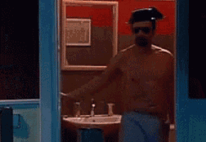 a shirtless man is standing in front of a white board holding a sword .