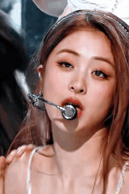a close up of a woman wearing a headband with a microphone in her mouth .