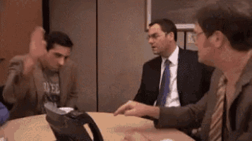 three men in suits and ties are sitting around a table talking to each other .