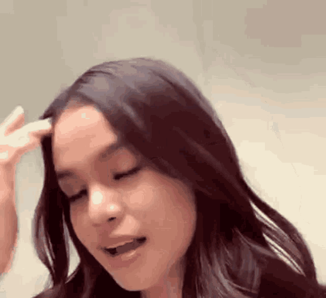 a close up of a woman 's face with her eyes closed and her hand on her forehead .