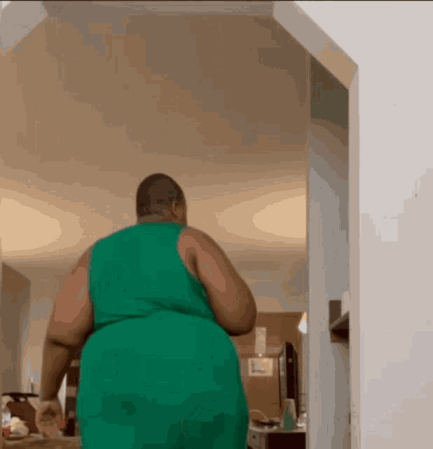 a man in a green tank top is walking through a doorway