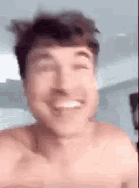 a shirtless man is smiling with his eyes closed and his mouth open .