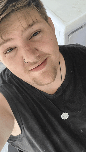 a man wearing a black tank top and a white necklace