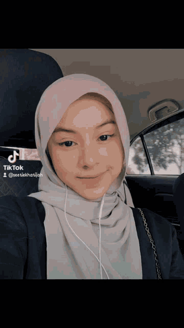 a woman wearing a hijab is sitting in a car with a tiktok watermark