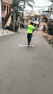 a man wearing a neon green jersey with the number 73 on it is riding a bike down a street