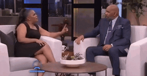 a man and a woman are sitting in chairs talking to each other on a television show .