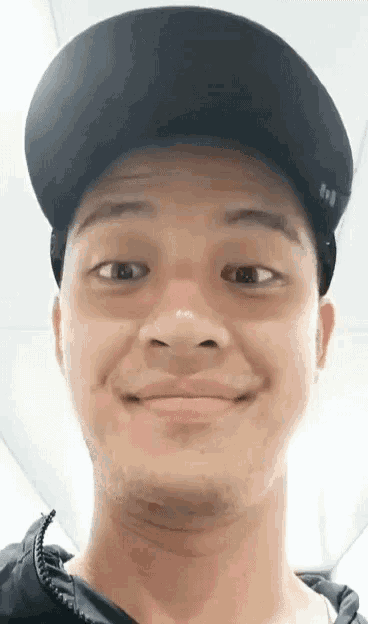 a man wearing a black hat is smiling and making a face