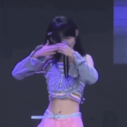 a young woman is covering her face with her hands while dancing on a stage .