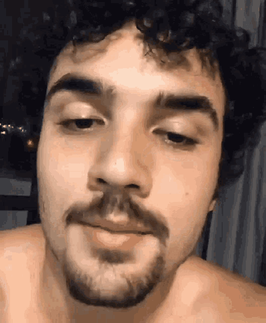 a man with curly hair and a beard is smiling for the camera