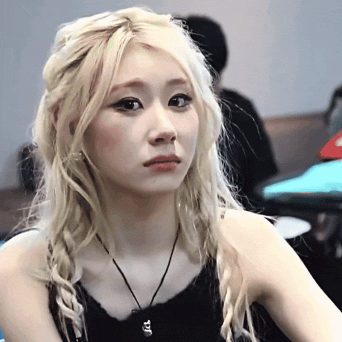 a woman with blonde hair is wearing a black tank top and a black necklace